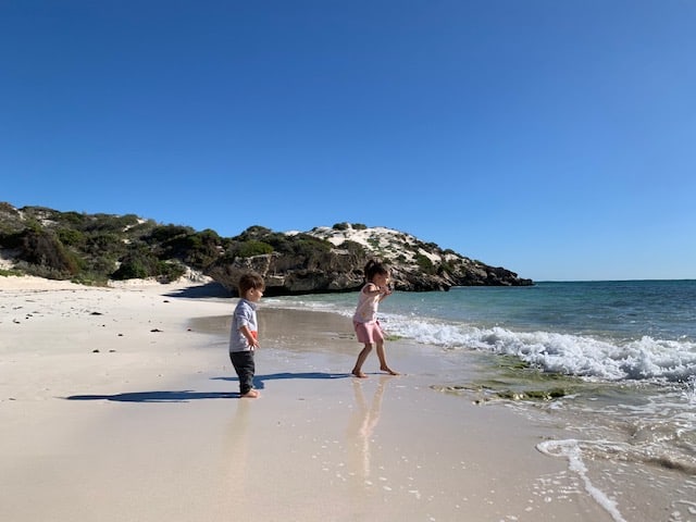 Two young kids running in the waves at Sandy Cape