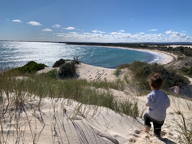 Young boy on sand dune looking out at Sandy Cape