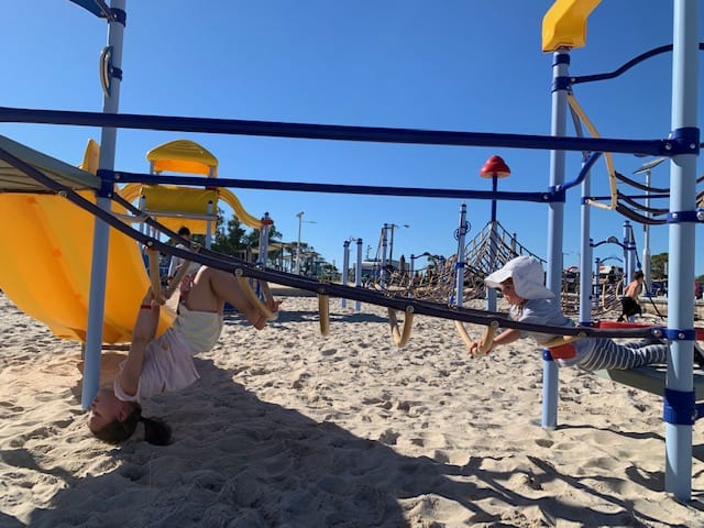 Two kids climbing on playground bars