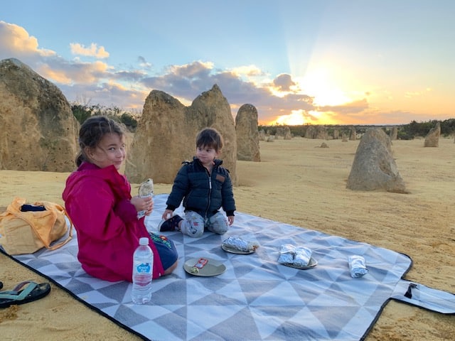 Two kids on a picnic blanket at The Pinnacles Desert at sunset